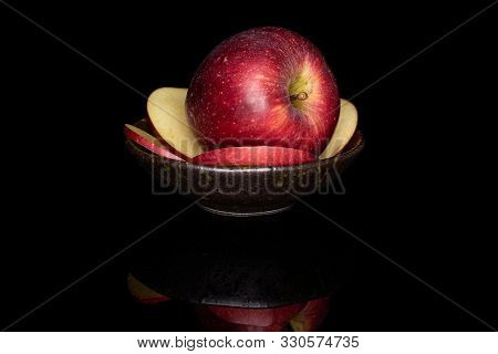 Group Of One Whole Four Slices Of Fresh Apple Red Delicious On Glazed Bowl Isolated On Black Glass