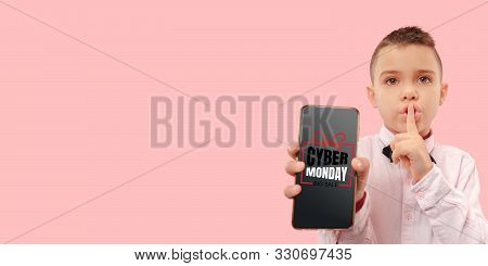 Portrait Of Young Caucasian Boy Showing Smartphone Screen On Coral Background. Whispering A Secret. 