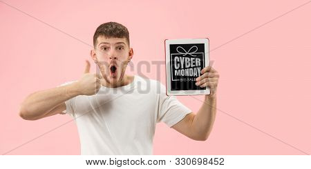 Portrait Of Young Man Showing Tablet Screen On Coral Background. Looks Astonished, Shocked. Concept 