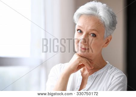 Happy Mature Woman Near Window Indoors, Space For Text. Smart Aging