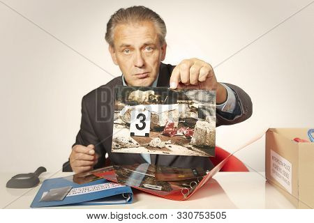 Police Officer Studying Collection Of Evidences On Table