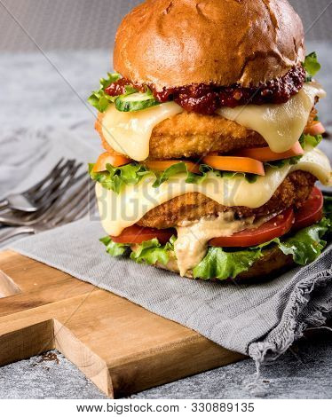 Homemade Chicken Burger With Fried Egg Tomato Lettuce Cucumber Dripping Mozzarella On Cutting Board 
