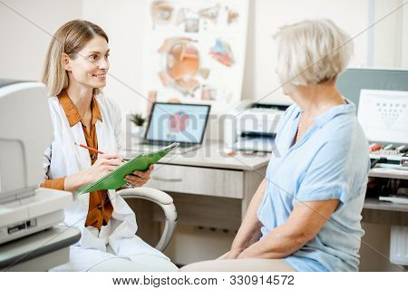 Senior Woman Patient Talking With Female Ophthalmologist During A Medical Consultation At The Ophtha