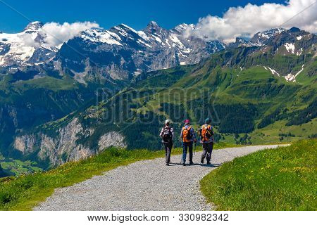 Tourists On Hiking Trail On Mountain Mannlichen, Popular Viewpoint In Swiss Alps, Switzerland.