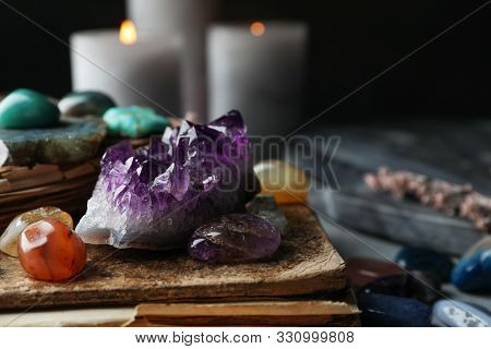 Many Different Gemstones And Blurred Candles On Background