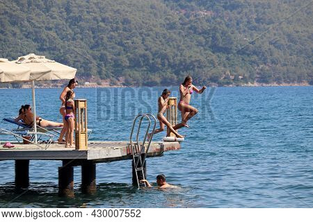 Hisaronu, Turkey​ -​ August 2021: Beach Holiday On Sea Resort, Woman And Girl In Swimwear Jump Into 