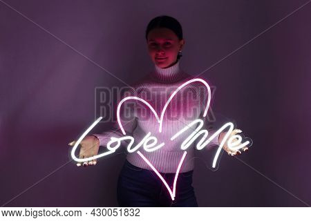 Beautiful Girl With Neon Signs. White And Pink Neon Heart With The Inscription Love Me. Trendy Style