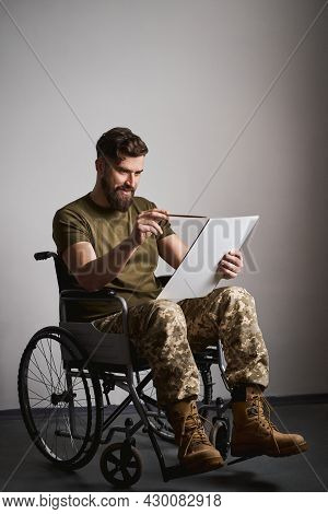 Disabled Soldier Sitting In A Wheelchair And Painting On A Canvas