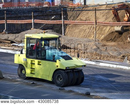 The Road Roller Compacts The Asphalt Surface On The Road. Road Roller At A Construction Site Against