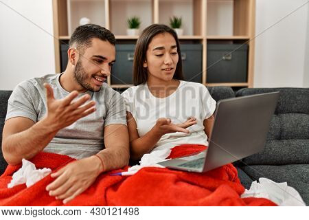 Young latin ill couple having medical teleconsultation using laptop at home.
