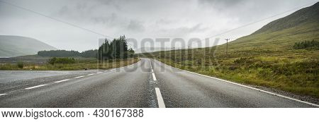 Horizontal Panoramic View Of A Road In The Highlands Area In Scotland, With Cloudy Skies.