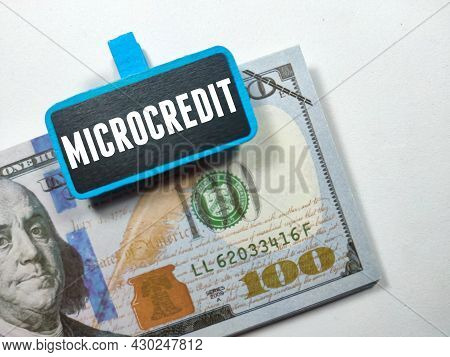 Business Concept.text Microcredit Writing On Colored Wooden Board With Fake Money On White Backgroun