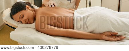 Asian Woman Enjoys Acupuncture Procedure Lying On Massage Table At Wellness Spa