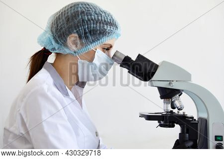 Female Scientist Looking Through Microscope In Modern Chemical Laboratory Doing Some Research. Analy