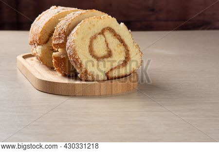 Rocambole, Sliced ​​rocambole Stuffed With Dulce De Leche On A Wooden Tray On A Table. Dark Backgrou