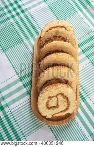Rocambole, Sliced ​​rocambole Stuffed With Dulce De Leche On A Wooden Tray On A Table With Checkered
