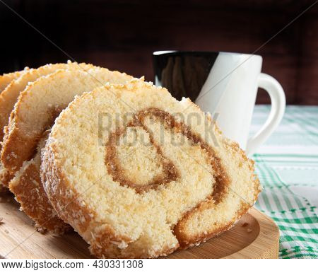 Rocambole, Sliced ​​roacambole Stuffed With Dulce De Leche On A Wooden Tray And A Cup On A Table Wit