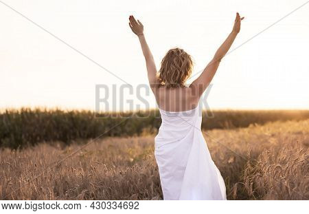 A Young Girl Stands Wrapped In A White Blanket Nens , Standing In A Field Of Wheat With Sunlight.