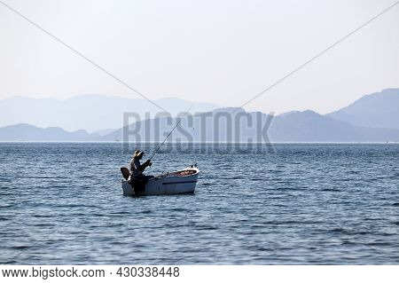 Hisaronu, Turkey - August 2021: Fishing Boat In The Sea On Background Of Mountains In Mist. Fisherma