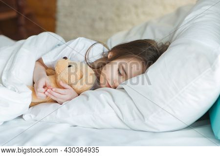 Baby Lying In Bed With Taddy Bear. Little Girl Sleeps With Knitted Toy