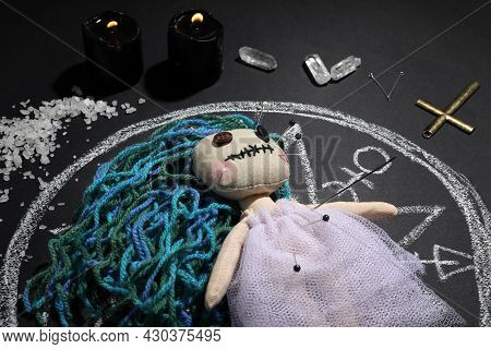 Female Voodoo Doll With Pins Surrounded By Ceremonial Items On Black Background