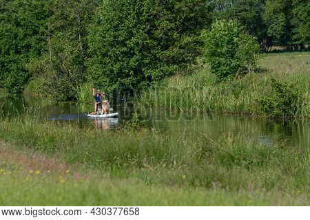 A Sun-tanned Woman In A T-shirt With Bikini Bottoms On A Sup Board. Together With Two Australian She