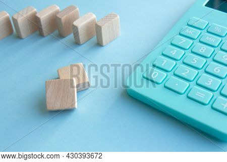 Mint Calculator And Stacks Of Wooden Cubes On Blue Background