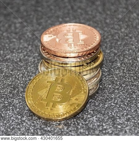 Vertical View Of A Glod Bitcoin Symbol On A Gold Coin Leaning On A Stack Of Crypto Coins All On A Bl
