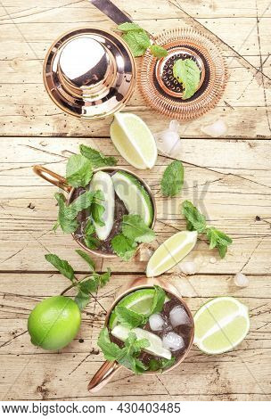 Moscow Mule Cocktails In Copper Mug With Lime, Ice, Ginger Beer, Vodka And Mint. Wooden Background, 
