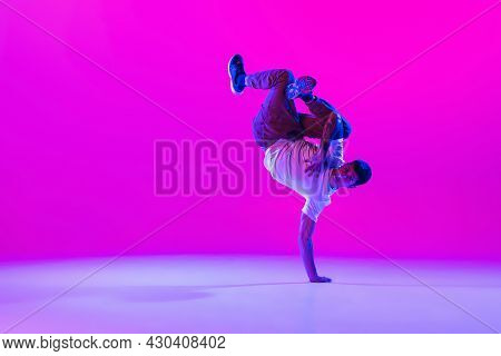 Young Stylish Man, Break Dancing Dancer Practicing Solo In Modern Clothes Isolated Over Bright Magen