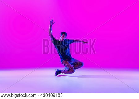 Portrait Of Dancing Man, Break Dancer In Action, Motion In Modern Clothes Isolated Over Bright Magen