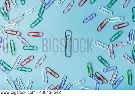 A Large Paper Clip Surrounded By Small Colored Paper Clips On A Blue Background