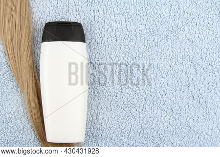 A Mock-up Of A White Bottle Of Cosmetic Shampoo And A Strand Of Blonde Hair Lies On A Blue Towel.hai