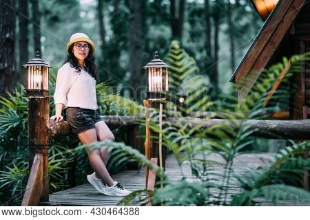 Winter Travel Relax Vacation,portrait Asian Female Tourist In White Dress With Hat Stands In Pinewoo
