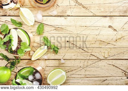 Moscow Mule Cocktails In Copper Mug With Lime, Ice, Ginger Beer, Vodka And Mint. Wooden Background, 