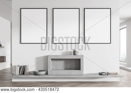Living Room Interior With Three Posters On White Wall Partition And Grey Fireplace With Shelf Below.
