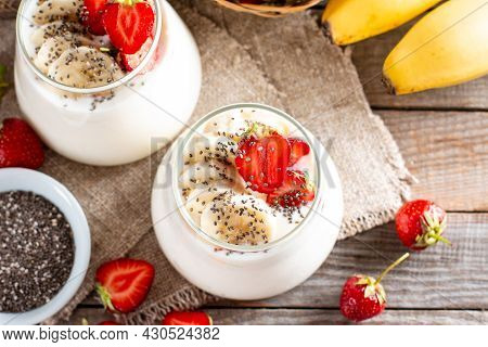 Dessert With Strawberries, Banana, Chia Seeds, Served In Glass Jars On A Wooden Table, Selective Foc