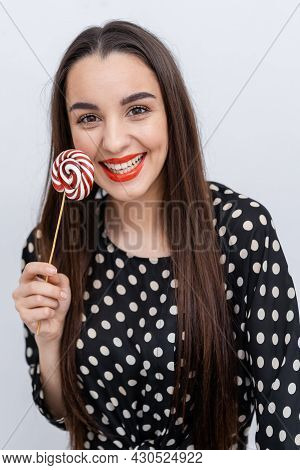 Happy Attractive Woman Smilling With Candies. Young And Pretty Girl In Black Wearings.