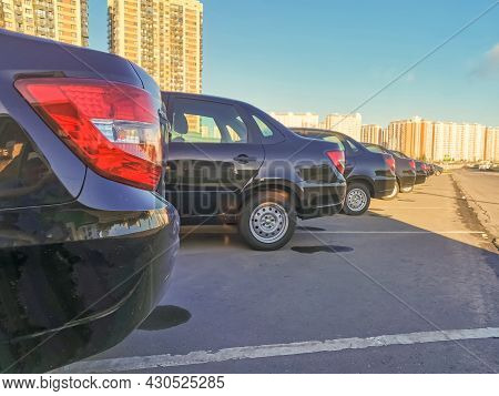 Many Black Executive Cars Standing In A Row Against The Background Of Buildings And A Blue Sky On A 