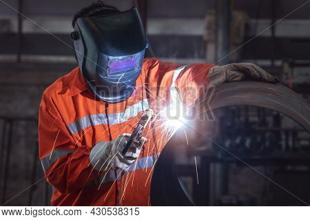 Industrial Worker With Protective Mask Welding Metal Pipe In A Factory