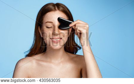 Beautiful Redhead Girl Holds Gua Sha Scrapper Tool For Face Massage, Close Eyes And Smile Happy, Mas