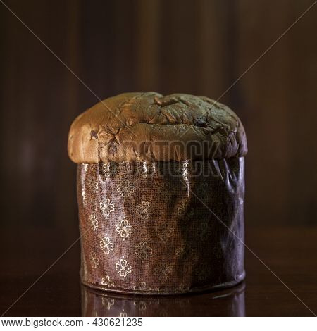 Panettone On The Wooden Table With Textured Brown Woody Background. Panettone Concept. Space For Tex