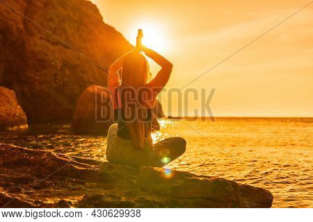 Young Woman With Long Hair In Black Swimsuit And Boho Style Braclets Practicing Outdoors On Yoga Mat