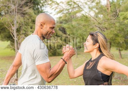 Close Up Of An Ahlete Couple Exercising By Holding With One Hand In The Park