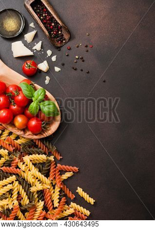 Fresh Raw Fusilli Pasta With Tomatoes In Wooden Bowl With Oil And Parmesan Cheese With Salt On Dark 