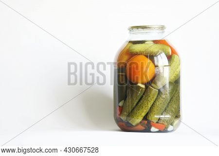 Preserved Tomatoes And Cucumbers In A Large Transparent Three-liter Jar On A White Background. The C