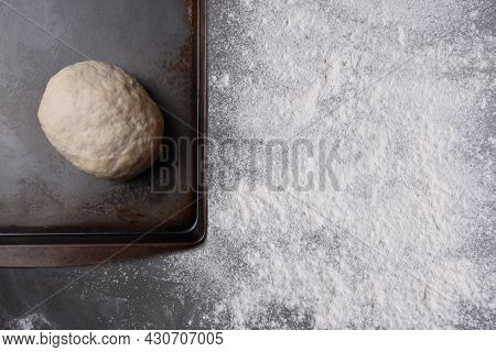 Baking Concept. A ball of bread dough ona baking sheet with rolling pin and counter top sprinkled with flour. 