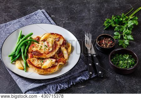 Pork Chops In Apple Cider Cream Sauce With Caramelized Sliced Apples Served With Green Beans On A Pl