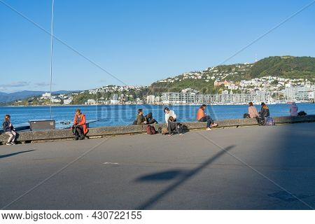 Wellington New Zealand - July 30 2021; People Enjoying, Relaxing And Sitting On Edge In Sun Along Th
