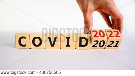 Symbol Of Covid-19 Pandemic In 2022. Doctor Turns Wooden Cubes And Changes Words 'covid 2021' To 'co